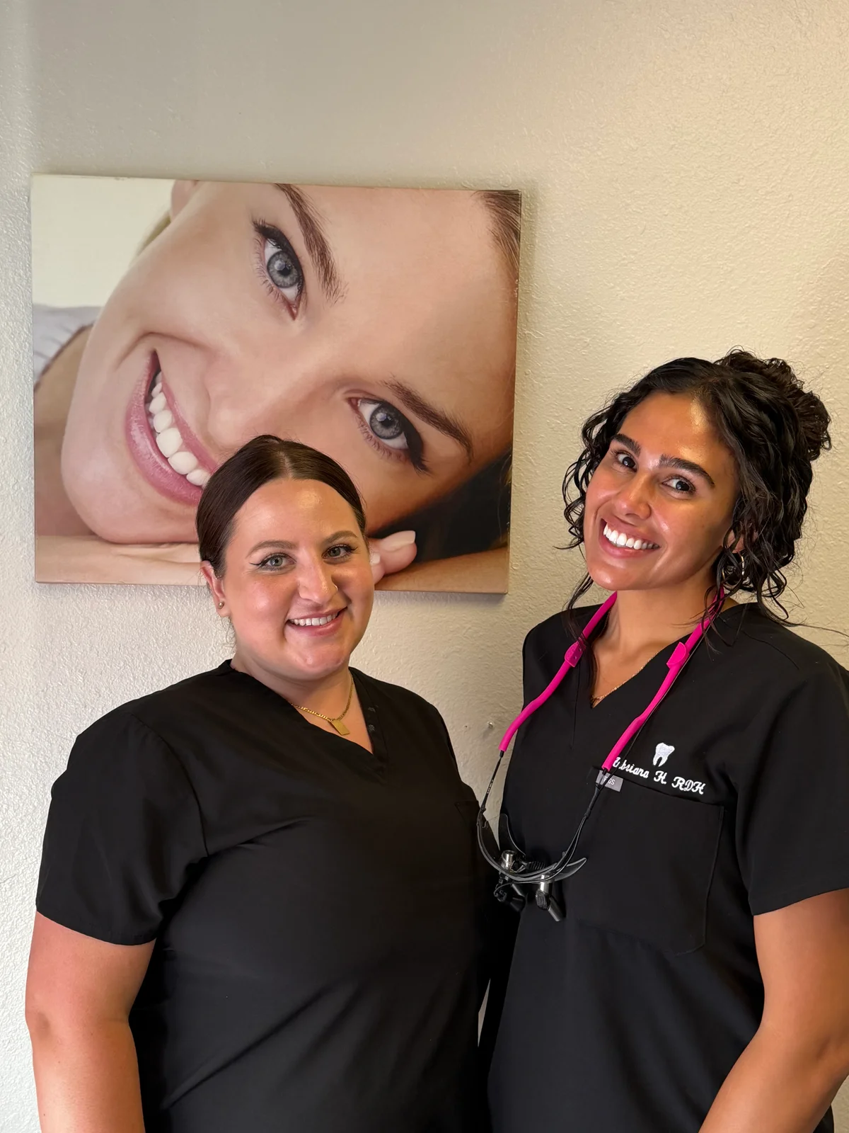 Two Mesa Dental Group team members smiling together in the office